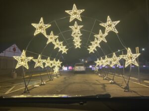 Rows of bright warm light stars arch over cars. 