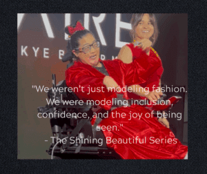 Mikelle, a woman in a wheelchair is wearing a silk long coat and is accompanies by Maryann a young woman with brown hair in a red dress designed for the fashion show.